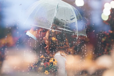在雨中，新娘和新郎在雨伞下接吻
